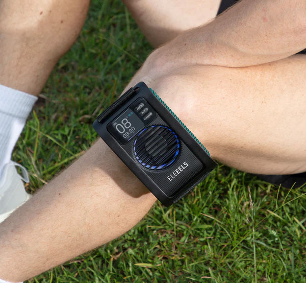 Das EleEELS X11 Kälte- und Wärmetherapiegerät ist mit einem schwarzen Gurt am Knie einer Person befestigt.