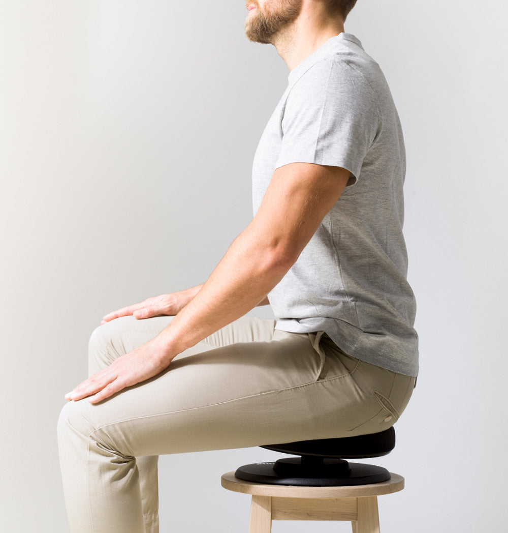 Mann sitzt seitlich auf dem Swedish Posture Balance Core Training Seat – fördert aktives Sitzen, stärkt die Körpermitte und verbessert die Haltung.